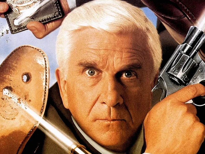 Frank Drebin có tạo hình trái ngược với các hành động tạo ra sự tương phản đến nực cười Frank Drebin có tạo hình trái ngược với các hành động tạo ra sự tương phản đến nực cười